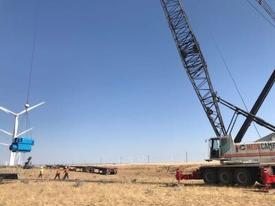 Crane lifting wind turbine blade on a wind farm